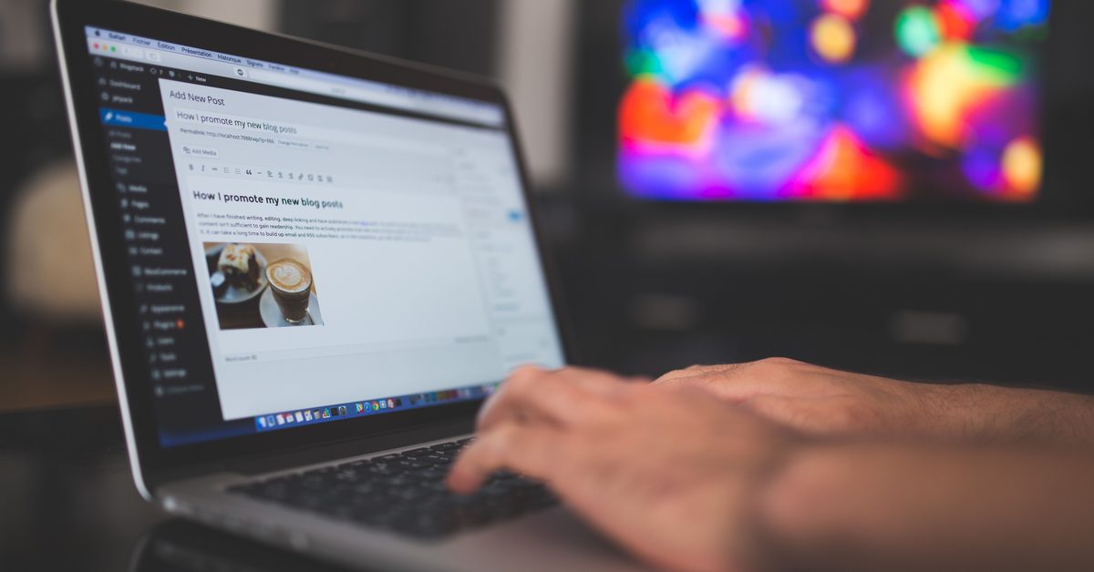 Handen op een laptop met de WordPress-editor open, tijdens het schrijven van een SEO-blog